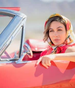 Woman with a colored scarf in a red car posing for a photo portrait