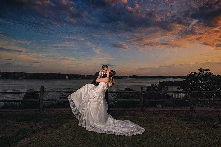 Wedding picture of a couple posing with a beautiful sunset behind them