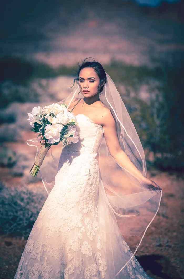 Bride with bouquet and flowing veil posing for wedding pictures