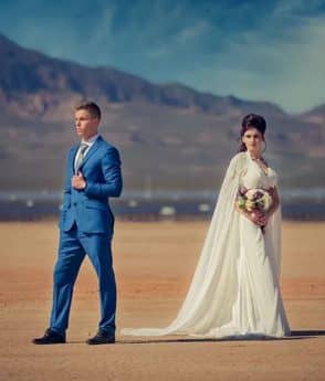 Young couple at a wedding photography session in the desert with mountains in the background
