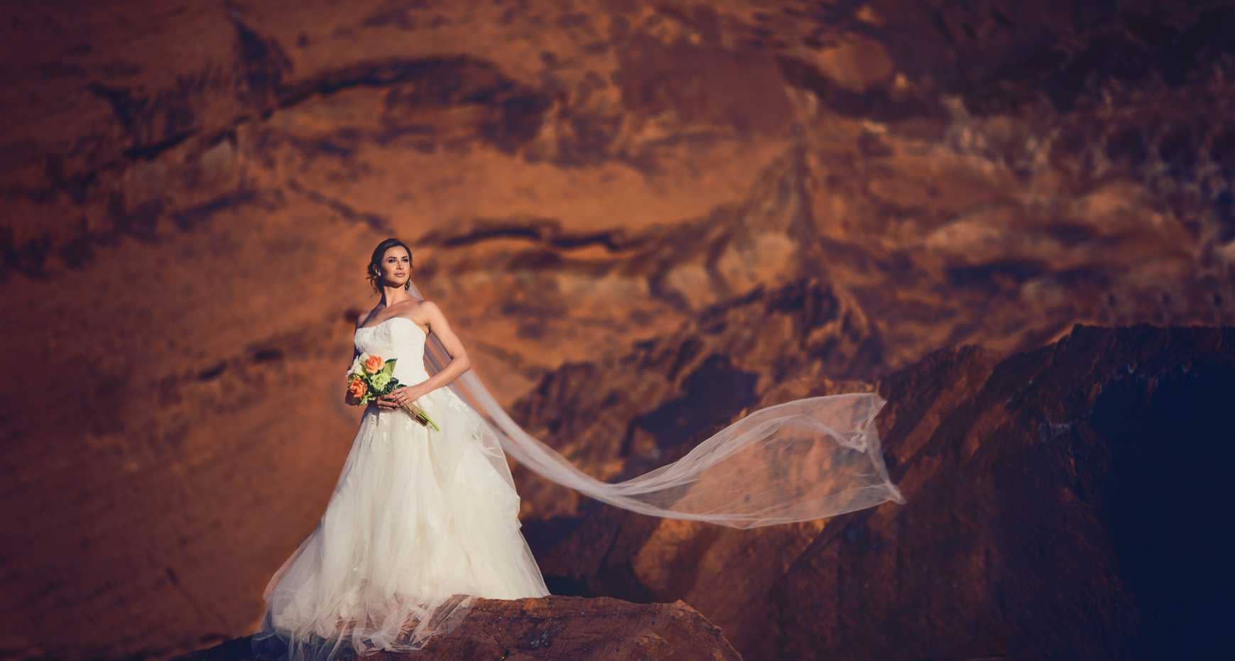 Dramatic bridal shot with flowing veil in the mountains by wedding photographers