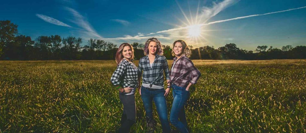 Three sisters posing for family portrait out in a field