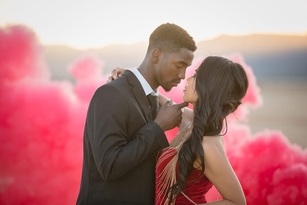 Romantic engagement photo with red smoke in backgrounc