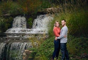 Couple posing for engagement photo beside a waterfall